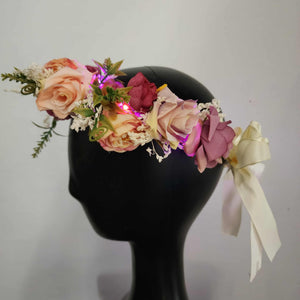 side view of flower crown with blush and pink flowers with greenery, pink LED lights, and a white satin bow tied in the back